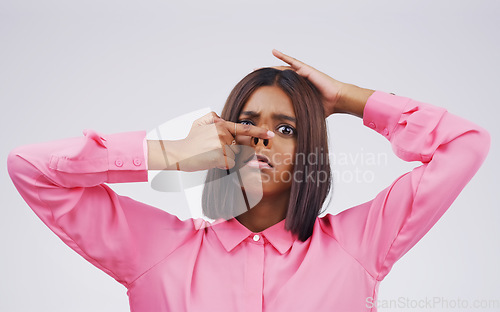 Image of Portrait, funny face and nose with an indian woman in studio on a gray background looking silly or goofy. Comedy, comic and quirky with a crazy young female person playing indoor for a joke or humor