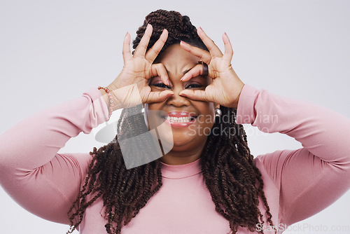 Image of Portrait, funny face and finger mask with a black woman laughing in studio on a white background for humor. Comic, comedy and hands as glasses with a playful young female person joking or having fun