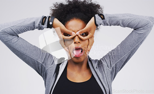 Image of Portrait, funny face and finger glasses with an african woman in studio on a gray background looking silly or goofy. Comedy, comic and mask with a crazy young female person joking for fun or humor