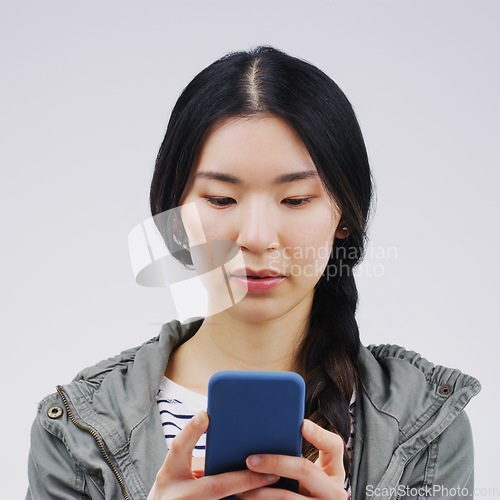 Image of Phone, online and face of Asian woman in studio for social media, internet and typing message. Communication, white background and Korean female person on smartphone for website, mobile app and text