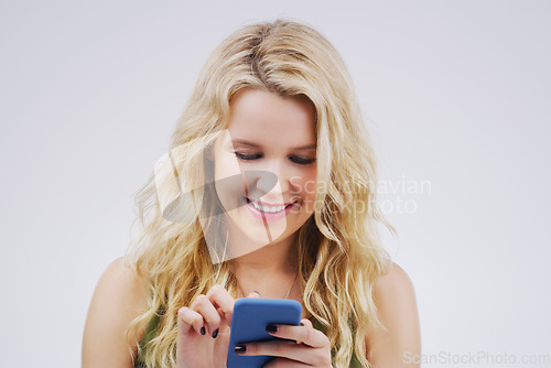 Image of Smile, social media and woman with a smartphone, typing and communication against a grey studio background. Female person, girl and model with a cellphone, network and online reading with happiness