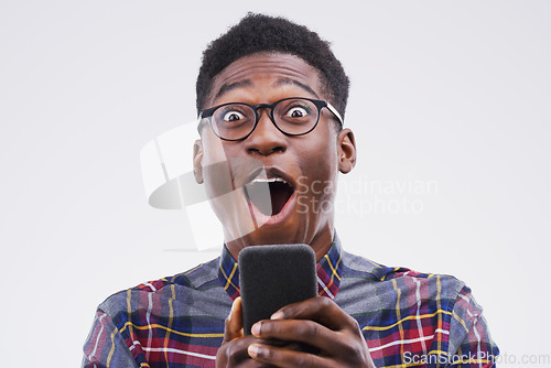 Image of Black man, surprise and phone in shock for winning, prize or good news against a white studio background. Shocked or surprised African male person with mobile smartphone, wow or lottery competition