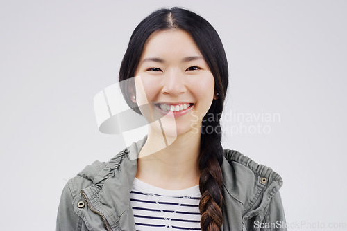 Image of Woman, portrait and asian with smile with studio white background is joyful with confidence. Female smiling, face and happiness with empowerment in China for excited youth with casual outfit.