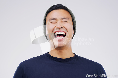 Image of Happy, laughing and man in studio with a casual outfit excited for a comic joke or funny story. Happiness, smile and face of an Asian male person with a positive facial expression by white background