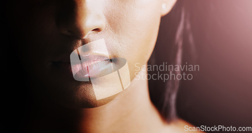 Image of Face, closeup of woman lips and in a black background for skincare with lens flare. Cosmetics or healthcare for skin, dermatology or treatment and female person in a studio backdrop with glow