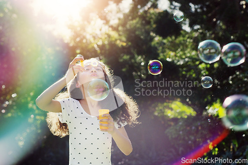 Image of Girl child, bubbles and backyard garden with mockup space in summer sunshine by trees for playing game. Female kid, blowing bubble and outdoor with soap, games and rainbow in nature, park and mock up