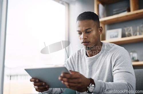 Image of Internet, tablet and man on couch reading social media post, email or streaming video on subscription service. Scroll, search and person with serious face and checking online movie website on sofa.