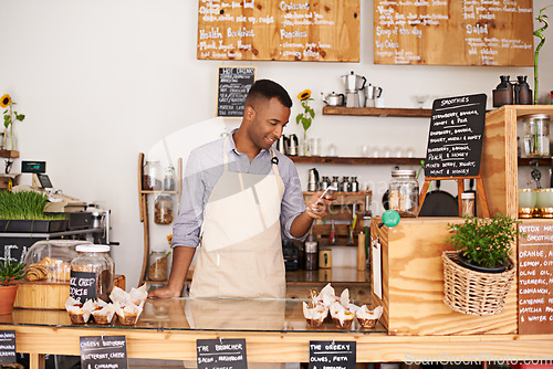 Image of Black man, coffee shop and store phone of an entrepreneur with happiness from small business. Cafe, mobile and barista looking at online app with a smile at bakery and restaurant feeling happy