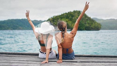 Image of Girl friends, peace hand sign and beach holiday with happiness and freedom on Thailand vacation. Women travel back and tropical island with a wood deck by the sea and ocean in summer outdoor by water