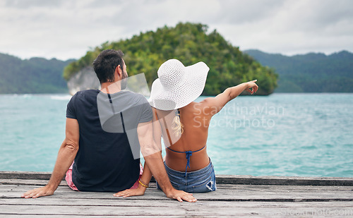 Image of Ocean, vacation and couple together on deck, dock or sitting on boardwalk to relax and enjoy the sea, water or landscape. People, man and woman on holiday, summer travel or tropical date in Bali