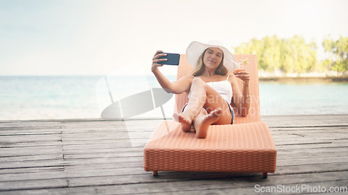 Image of Young woman, lounge selfie and cocktail on holiday by the ocean on a deck chair with a smile. Female person, travel and Maldives island in summer taking a photo for a profile picture and social media