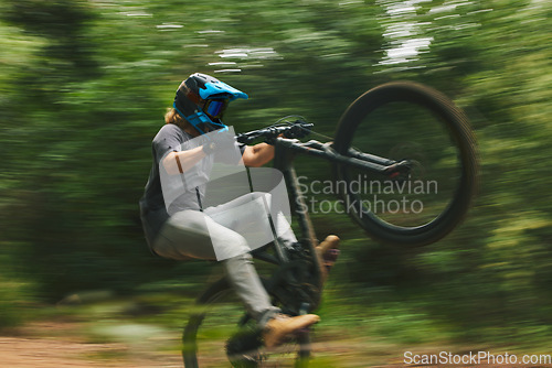 Image of Fitness, trail and man doing a trick on a bike while riding for competition practice in the woods. Extreme sports, blur motion and male athlete biker with skill training or exercise in outdoor forest