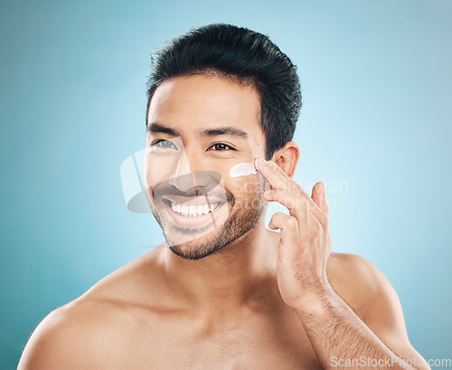 Image of Skincare, beauty and man with face cream in a studio for a natural, wellness and health routine. Happy male model with facial spf, lotion or moisturizer for dermatology treatment by a blue background