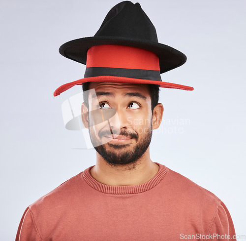 Image of Confused, hats and young man in a studio with a thinking, idea or contemplating face expression. Pensive, thoughtful and Indian male person with fun head accessories isolated by a white background.