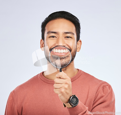 Image of Portrait, teeth and man with a magnifying glass, smile and search against a studio background. Face, male person and model with a tool, zoom and happiness with oral health, dental hygiene and care