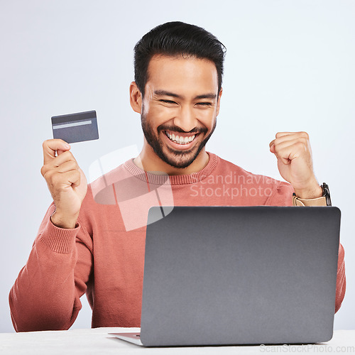 Image of Excited man, laptop and credit card for online shopping, e commerce and payment in studio. Asian male person with technology and hand to celebrate savings, promotion or sale on a fintech website