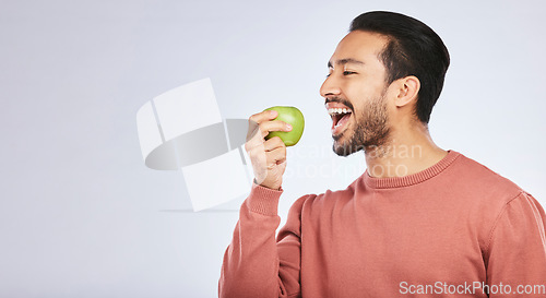 Image of Green apple, eating and happy man isolated on a white background for healthy food, diet and detox space. Vegan person, nutritionist or asian model with fruit for self care or lose weight in studio