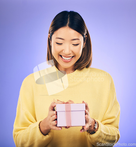 Image of Happy, smile and woman with a gift box in a studio for a birthday, achievement or celebration. Happiness, excited and Asian female model with a present package for party isolated by purple background