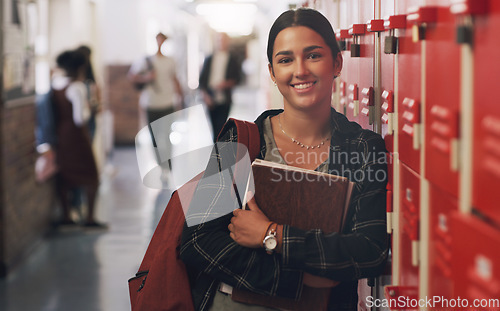 Image of Portrait, education and notebook break with a girl by her locker in the hallway of her school. Learning, university or scholarship with a college pupil holding research books for studying knowledge