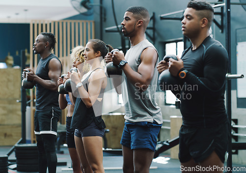 Image of Weightlifting, fitness and people with kettlebell in gym for training, exercise and workout class. Teamwork, body builder and serious men and women lift weights for challenge, wellness and strength