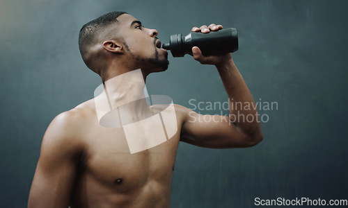 Image of Fitness, man and drinking water on wall background after workout, exercise and training at a gym. Bottle, hydration and male relax after cardio, bodybuilding or challenge at sports center with space