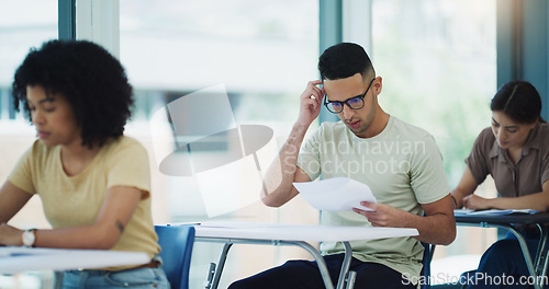 Image of Thinking, man and education test in a classroom with writing and student learning at a university. College exam, school and male person planning with document in a lecture hall with stress and paper