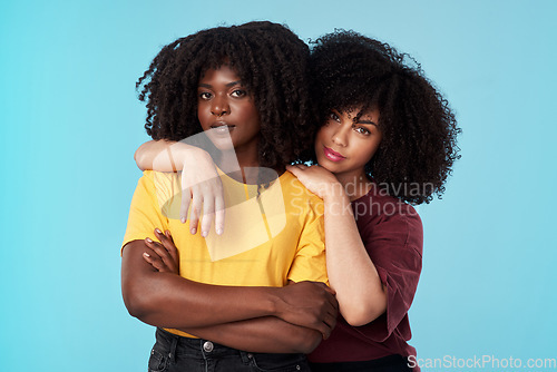 Image of Portrait, diversity and support with friends on a blue background in studio together for freedom or empowerment. Love, trust and an attractive young black female standing arms crossed with a friend