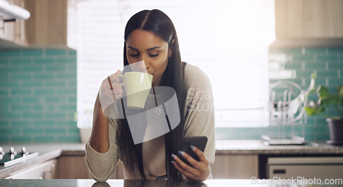 Image of Phone, texting and woman with coffee in a kitchen relax with social media, app or reading. Smartphone, streaming and female drinking tea in her home in the morning, calm and peaceful in her apartment