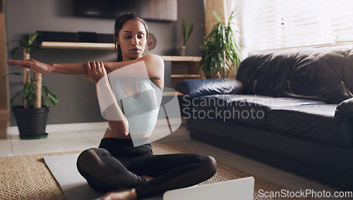 Image of Stretching, Indian woman and laptop for online yoga on living floor for training, balance or healthy lifestyle. Arm, stretch and female person start fitness tutorial for pilates or meditation workout