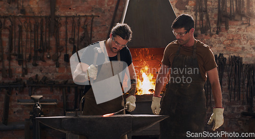 Image of Hammer, anvil and fire with men working in a forge for metal work manufacturing or production. Industry, welding and trade with blacksmith professionals in a workshop, plant or industrial foundry