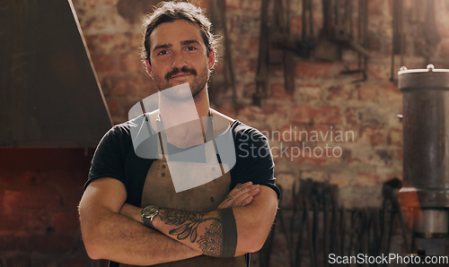 Image of Portrait, industry and a man arms crossed in a workshop for metal work, engineering or construction. Manufacturing, production and a confident young male industrial blacksmith in a factory or plant