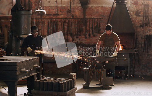 Image of Hammer, anvil and sparks with men working in a forge for metal work manufacturing or production. Industry, welding and trade with a young male blacksmith in a workshop, plant or industrial foundry