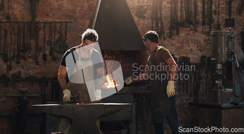 Image of Hammer, anvil and fire with men working in a foundry for metal work manufacturing or production. Industry, welding and trade with blacksmith craftsmen in a steel workshop, plant or industrial forge