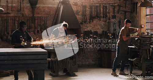 Image of Hammer, anvil and sparks with men in a workshop for metal work manufacturing or production. Industry, welding and trade with blacksmith professionals at work in a factory, plant or industrial forge