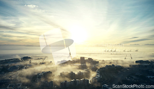 Image of City, sea and sunrise landscape with building skyline and ocean background in Cape Town. Fog, clouds and drone of sky with urban cityscape and sunlight outdoor in the morning by water and buildings