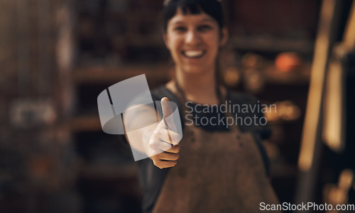 Image of Thumbs up, factory and woman blacksmith in workshop for industry, manufacturing and manual labor. Industrial warehouse, welding and female person with hand sign for steel, iron and metal production