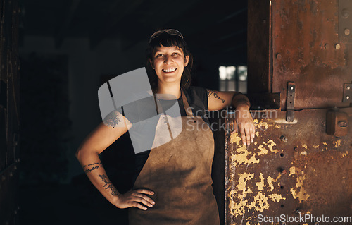 Image of Woman blacksmith, portrait and smile in factory, industry and trade for entrepreneurship at artisan job. Small business owner, female entrepreneur and labor in industrial warehouse with manufacturing