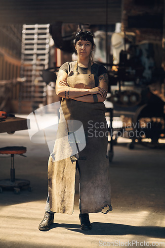 Image of Blacksmith, workshop and portrait of woman with crossed arms for industry, manufacturing and welding. Industrial factory, warehouse and female person for steel, iron and metal production in foundry