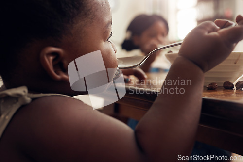 Image of Black child, cereal spoon and eating baby in a home kitchen with food and bowl at breakfast. African girl, nutrition and youth in a house with hungry kid relax with healthy snack and kids at morning