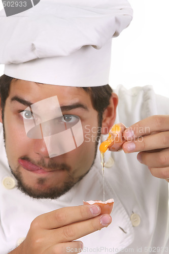 Image of young funny chef cracking an egg