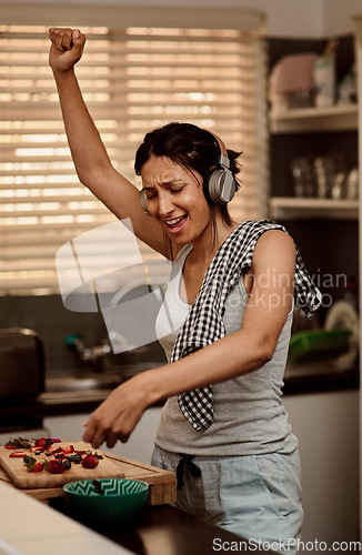 Image of Music headphones, singing and woman cooking with strawberry. Sing, kitchen and female person making snack with fruit for healthy nutrition while dancing to audio, sound and radio podcast in home.