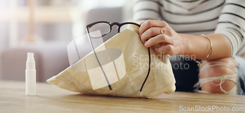 Image of Hand, closeup of woman cleaning glasses and spray bottle with chemical liquid, fabric cloth and hygiene. Clean spectacles, eyewear and female cleaner at home with eye care with lens maintenance