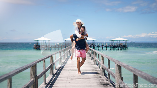 Image of Ocean, dock and a couple playing on vacation for a piggy back, freedom and to relax outdoor with love. A man and woman together on holiday, tropical travel and summer adventure in nature with water