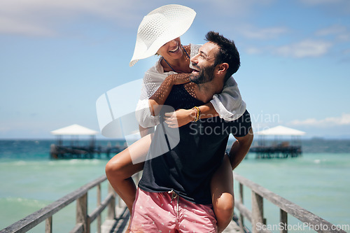 Image of Couple, piggyback and beach deck on a tropical island with love and laughing on holiday. Summer vacation, travel smile and Maldives walk in nature with freedom and happiness by the ocean and sea