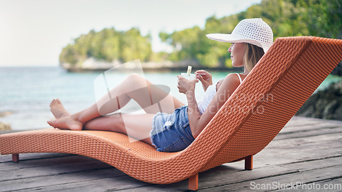 Image of Chair, ocean and woman relax with a drink outdoor on a vacation, holiday or adventure in nature. Female person on tropical lounger, travel and deck with lake water in summer for zen, peace and calm