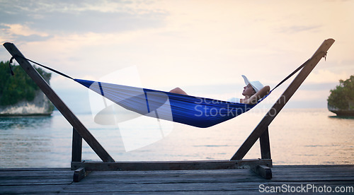 Image of Sunset, hammock and woman on vacation, relax and view on weekend break, getaway and peace. Female person, girl and tourist on summer holiday, water and peace with traveler lying down and tourism