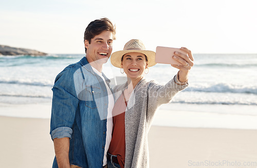 Image of Young couple, beach selfie and smile in summer sunshine for love, romance or happy for social media post. Man, woman and profile picture for blog, app or internet by ocean, waves or sea for vacation