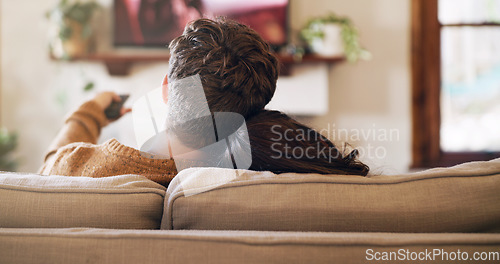 Image of Watching tv, couple and love in a home on a living room sofa with bonding feeling relax. Cuddle, lounge couch and house with a television and movie with people back streaming series with remote