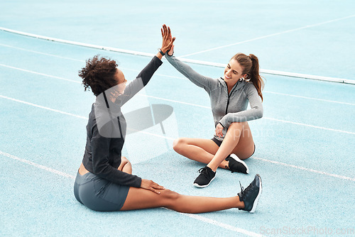 Image of Happy woman, high five and partnership on stadium track for running, workout or exercise together in teamwork. Sports women touching hands in support, fitness or friends for training motivation