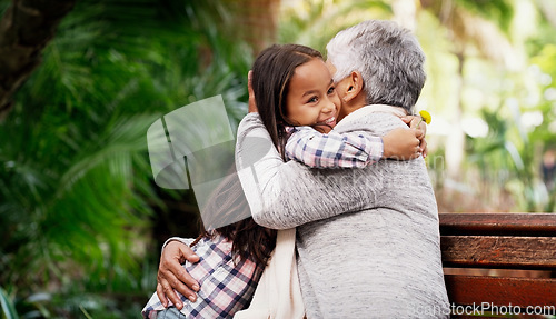 Image of Happy, young girl and grandmother hug or a flower for senior woman or child with care or bond with pensioner and summer day in the park. Joy, kid and elderly person embrace on the bench with love